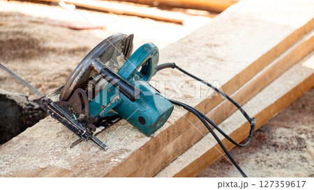 Electric circular saw on timber stack in a wood workshop 127359617