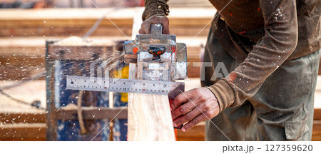Carpenter hand using angle ruler for wood squaring and planing wooden plank by electric planer 127359620