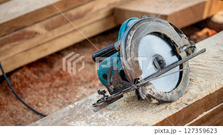Electric circular saw on timber stack in a wood workshop 127359623