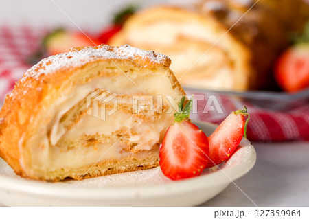 Sliced rolls with custard. The dessert is decorated with fresh strawberries. 127359964