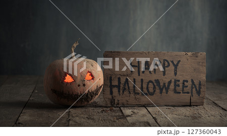 恐ろしい表情の腐敗ハロウィンかぼちゃと古い木製看板 | ダークホラー 127360043