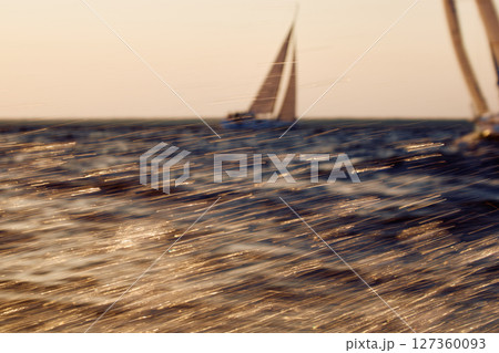 Sailing regatta in the Gulf of Finland at sunset, two sailing yachts competing in a race, splashing water from under the boats, teamwork, board the boat 127360093