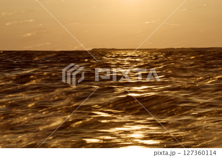 The wave splashes into splashes in the rays of sun at sunset 127360114