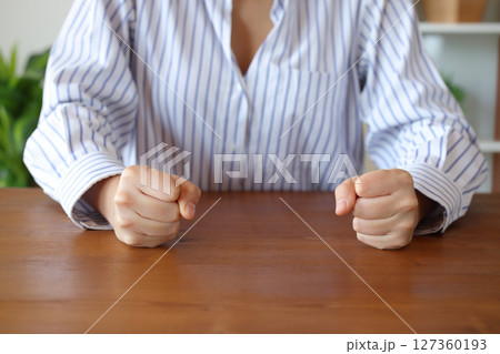 Angry woman clenching fists on a table 127360193