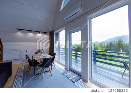 Cozy Modern Dining Space with Scenic Views in a Charming Mountain Getaway Featuring Large Windows to Bring the Outdoors In and Inviting Interior Decor for a Relaxing Atmosphere 127360236