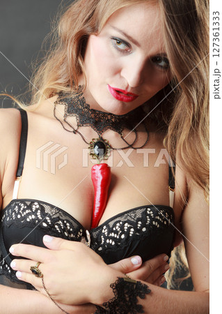 Woman wearing sexy lingerie holding chilli on chest Woman wearing sexy lingerie holding chilli on chest 127361333