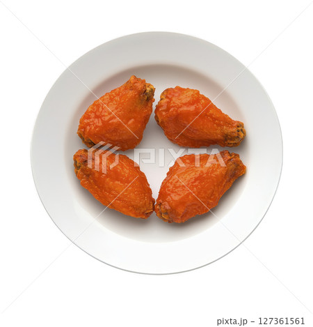 Four spicy buffalo chicken wings are arranged on white plate, showcasing their vibrant orange glaze. wings appear crispy and flavorful, perfect for savory snack or appetizer 127361561
