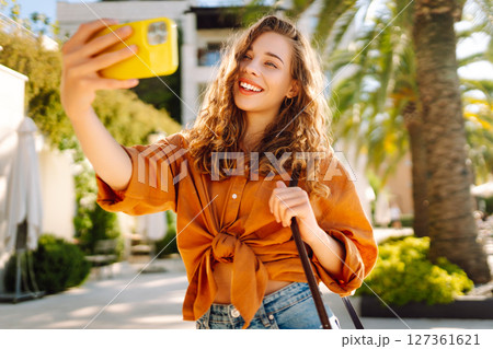 Tourist takes selfie with smartphone camera while walking along sunny streets of resort town. Tourist takes selfie with smartphone camera while walking along sunny streets of resort town. 127361621