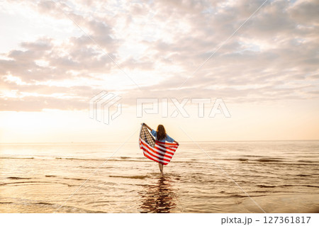 Young woman with American flag on beach. Patriotic holiday. Independence Day concept Young woman with American flag on beach. Patriotic holiday. Independence Day concept 127361817