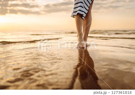 Woman leg close up walking on sand relaxing in beach at sunset. Sexy lean and tanned legs. 127361818