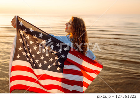 Young woman with American flag on beach. Patriotic holiday. Independence Day concept 127361822