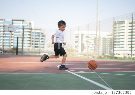 Boy Dribbling Basketball While Running across the Court Boy Dribbling Basketball While Running across the Court 127362393