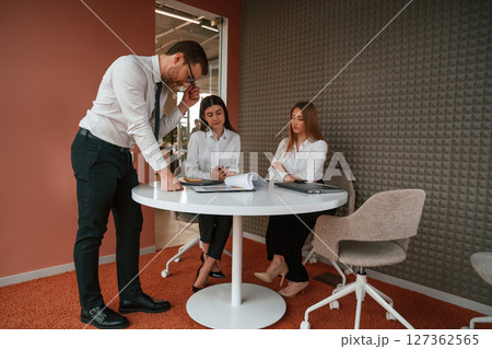 Man is talking, showing documents, plan of the project. Three business people are working in the office together 127362565