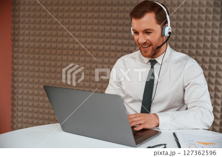 Using laptop. Handsome man in formal clothes is in the office 127362596