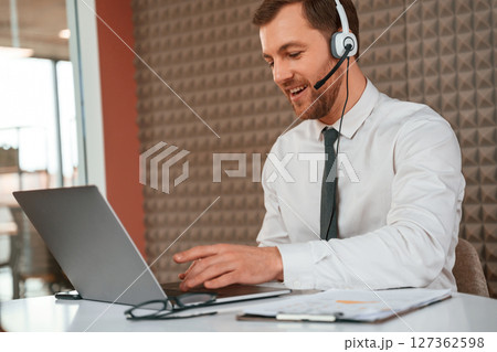 Using laptop. Handsome man in formal clothes is in the office 127362598