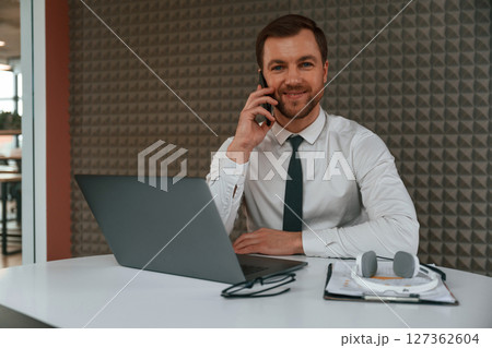 Handsome man in formal clothes is working by laptop in the office Handsome man in formal clothes is working by laptop in the office 127362604