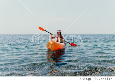Kayaking Woman Sea Paddle - A woman paddles a kayak in the sea on a sunny day. 127363137