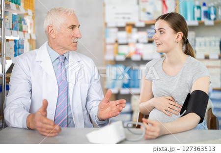 Experienced male pharmacist measuring girl blood pressure with tonometer Experienced male pharmacist measuring girl blood pressure with tonometer 127363513