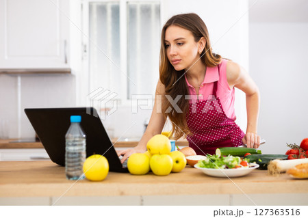Housewife preparing food in kitchen at home 127363516
