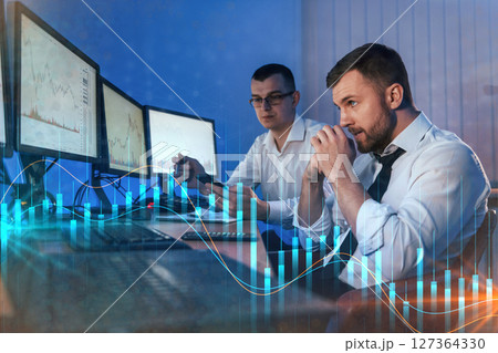 Graphs and data. Different information on screens. Two stock traders working in the office with exchange technology Graphs and data. Different information on screens. Two stock traders working in the office with exchange technology 127364330