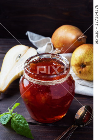 Homemade pear jam in a jar and fresh pears on a wooden background. Homemade pear jam in a jar and fresh pears on a wooden background. 127364376