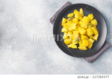 Delicious baked potatoes with spices cheese and rosemary on a black ceramic plate, a gray concrete background, copy space. Delicious baked potatoes with spices cheese and rosemary on a black ceramic plate, a gray concrete background, copy space. 127364377