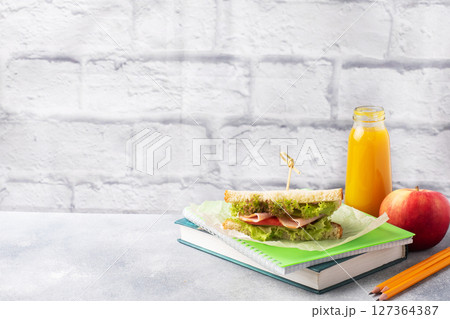Snack for school with sandwich, fresh Apple and orange juice. Colorful school supplies, Copy space, 127364387