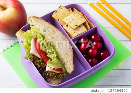 Delicious healthy sandwich in a lunch box, cookies and cherries. Take lunch with you to school or the office. Delicious healthy sandwich in a lunch box, cookies and cherries. Take lunch with you to school or the office. 127364392