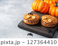 Cookies with cream paste in the shape of monsters for Halloween celebration. Funny homemade faces made of oatmeal cookies and boiled condensed milk. copy space 127364410