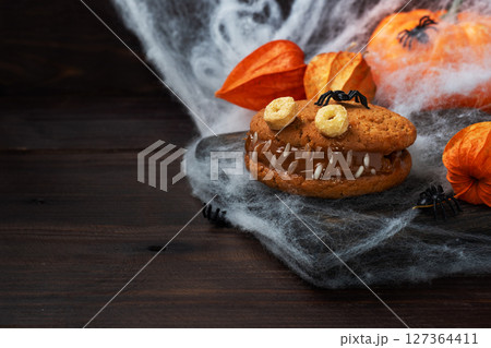 Cookies with cream paste in the shape of monsters for Halloween celebration. Funny homemade faces made of oatmeal cookies and boiled condensed milk. copy space 127364411