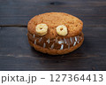 Cookies with cream paste in the shape of monsters for Halloween celebration. Funny homemade faces made of oatmeal cookies and boiled condensed milk. copy space 127364413
