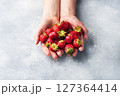 handful Juicy ripe strawberries in the hands on a concrete background. Sweet healthy dessert, vitamin harvest. copy space. 127364414