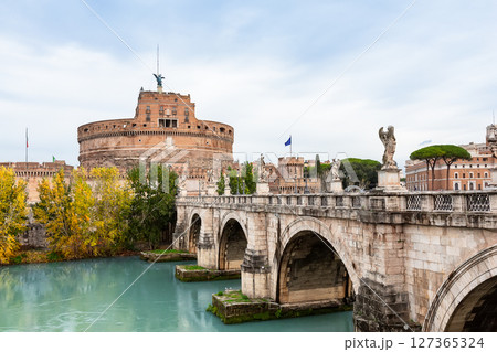 Castel Sant'Angelo and the Sant'Angelo bridge over Tiber river against cloudy sky in Rome, Italy. Castle of Holy Angel and St. Angel bridge in Rome, Italy. 127365324