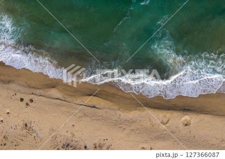 Aerial view of a remote sandy beach and sea waves Aerial view of a remote sandy beach and sea waves 127366087