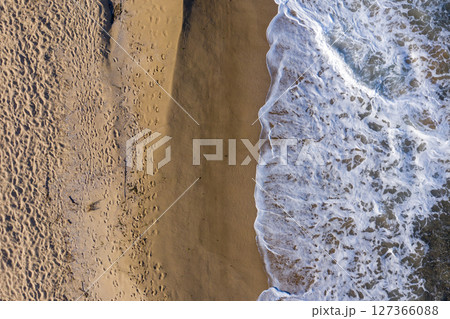 Aerial view of sea waves and a remote secluded sandy beach 127366088