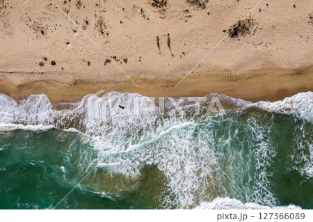 Aerial view of a remote sandy beach and sea waves 127366089