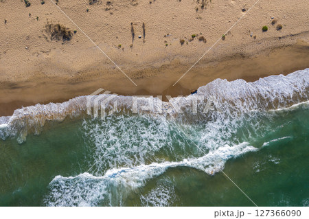 Aerial view of sea waves and a remote secluded sandy beach 127366090