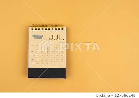 July 2025 calendar from brown craft paper on yellow color background. July 2025 calendar from brown craft paper on yellow color background. 127366249