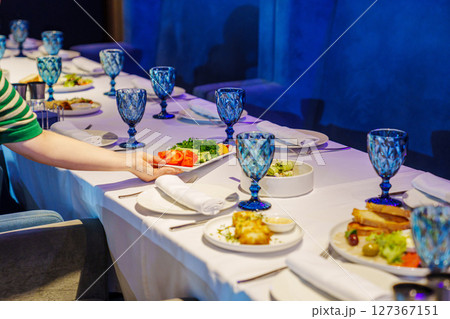 A festive table with cutlery and snacks in a dark room of the restaurant. A festive table with cutlery and snacks in a dark room of the restaurant. 127367151