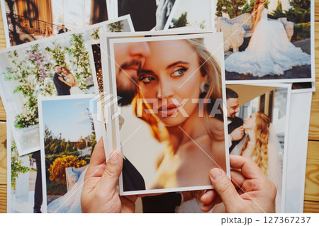 Men's hands put on the table and show wedding photos. 127367237