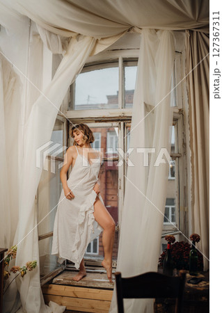 Beautiful and slender young woman in a long white dress with bare feet. Beautiful and slender young woman in a long white dress with bare feet. 127367311