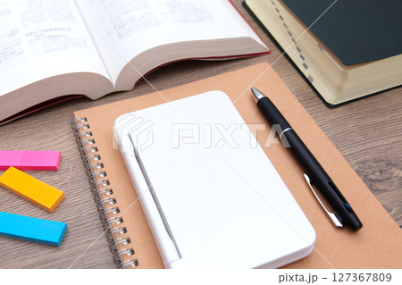 机の上に置かれた電子辞書、辞書、参考書、ノート、ボールペン 机の上に置かれた電子辞書、辞書、参考書、ノート、ボールペン 127367809