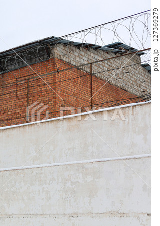 High Brick Wall with Barbed Wire Surrounding a Prison: A Symbol of Confinement and Security High Brick Wall with Barbed Wire Surrounding a Prison: A Symbol of Confinement and Security 127369279
