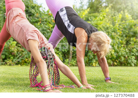 Girl and mature woman together raising leg and bending forward . 127370488