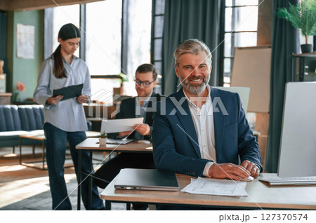 Man is smiling. Group of business people are working in the modern office Man is smiling. Group of business people are working in the modern office 127370574