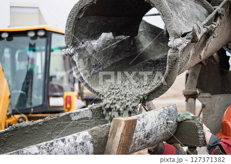 Concrete mixing process at construction site with machinery and workers involved Concrete mixing process at construction site with machinery and workers involved 127371382