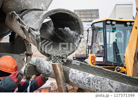 Concrete pouring during construction at a building site in winter months with heavy machinery nearby Concrete pouring during construction at a building site in winter months with heavy machinery nearby 127371399