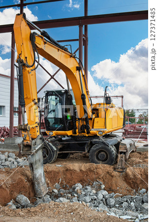 Excavator digging a trench at a construction site under a clear blue sky Excavator digging a trench at a construction site under a clear blue sky 127371485