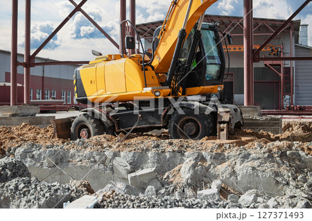 Construction equipment actively working on a building site during the day Construction equipment actively working on a building site during the day 127371493