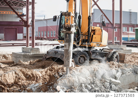 Construction equipment breaking ground at a building site in urban area during daylight hours 127371503